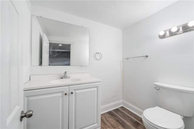 bathroom with wood finished floors, vanity, toilet, and baseboards