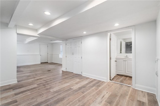 finished below grade area featuring light wood finished floors, recessed lighting, and baseboards