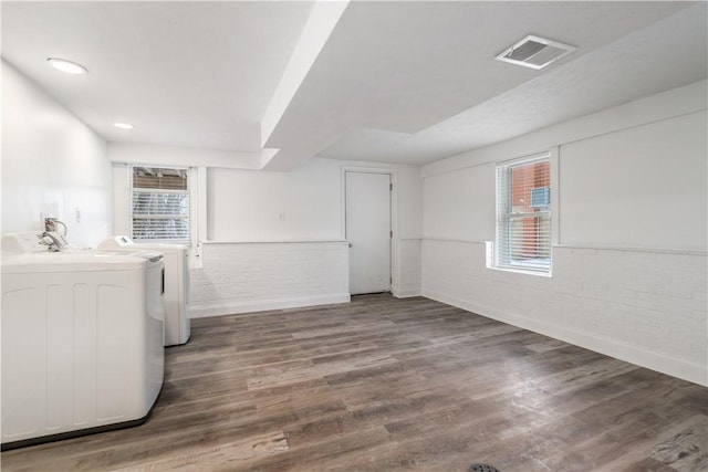 clothes washing area with baseboards, visible vents, wood finished floors, and washing machine and clothes dryer