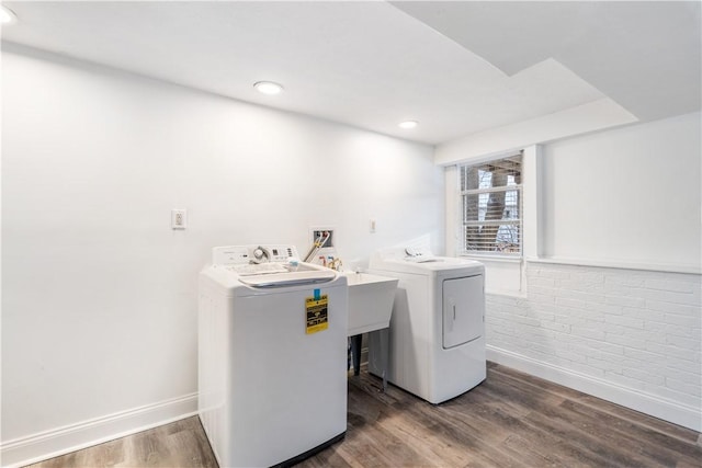 washroom with brick wall, laundry area, separate washer and dryer, wood finished floors, and baseboards