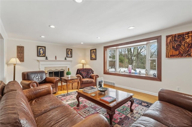 living room with baseboards, visible vents, wood finished floors, a fireplace, and recessed lighting