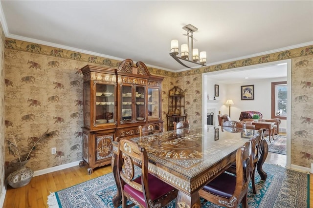 dining room with crown molding, a fireplace, baseboards, and wood finished floors