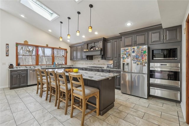 kitchen featuring a center island, a warming drawer, stainless steel appliances, lofted ceiling with skylight, and light stone countertops