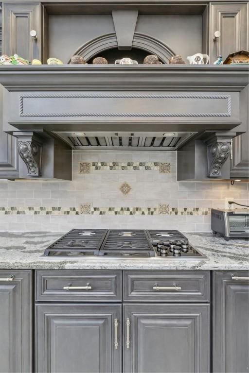 kitchen with a toaster, tasteful backsplash, stainless steel gas cooktop, and gray cabinets