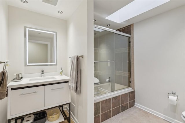 bathroom with tile patterned flooring, a skylight, vanity, and toilet