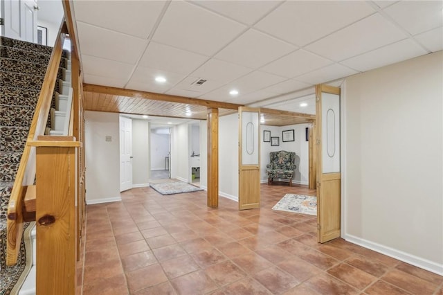 finished basement featuring recessed lighting, visible vents, a drop ceiling, baseboards, and stairs