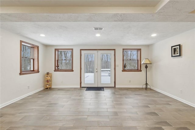 empty room with french doors, visible vents, and baseboards