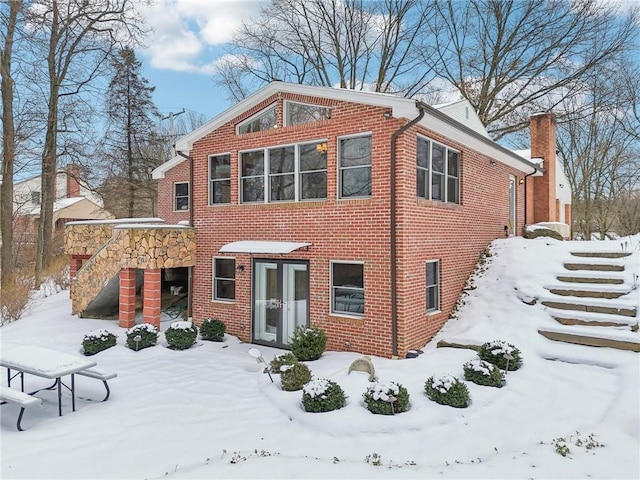 view of front of property with french doors, brick siding, and stairway