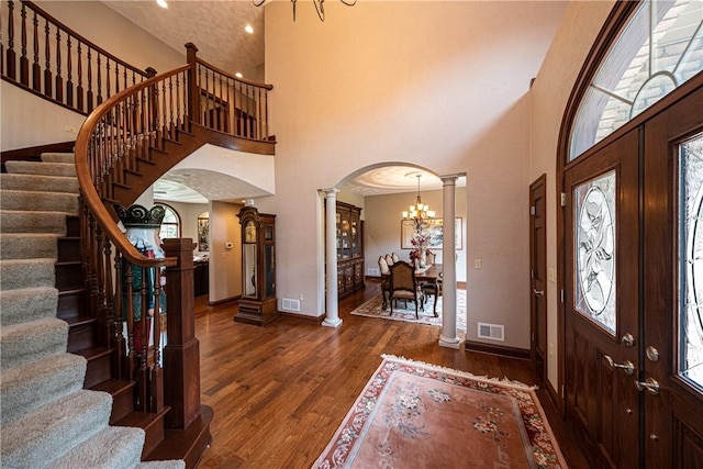 foyer entrance featuring arched walkways, visible vents, decorative columns, and wood finished floors