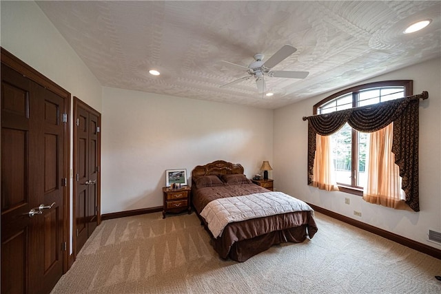 bedroom with light carpet, a textured ceiling, and baseboards