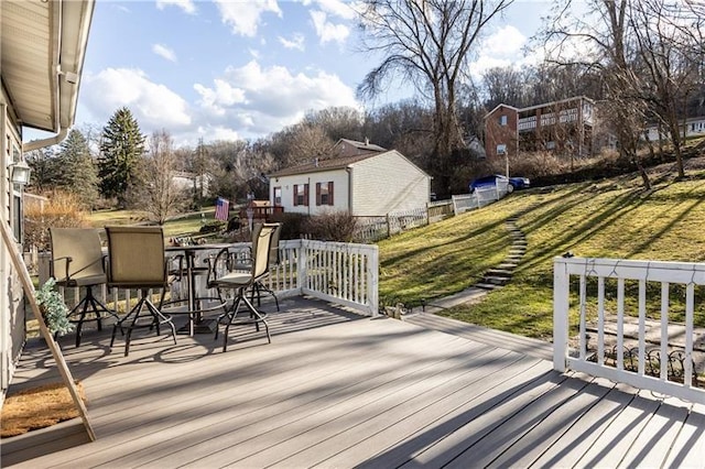 wooden deck featuring outdoor dining space and a lawn