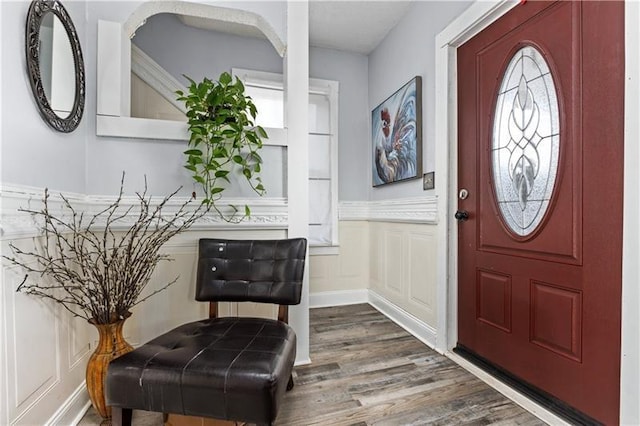 foyer with dark wood-type flooring, a wainscoted wall, and a decorative wall