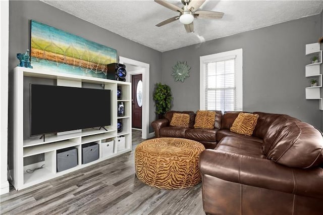 living area with a textured ceiling, a ceiling fan, and wood finished floors