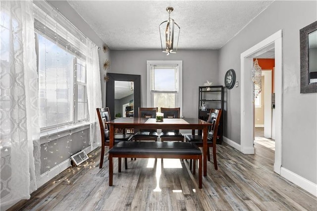 dining room featuring visible vents, a textured ceiling, baseboards, and wood finished floors