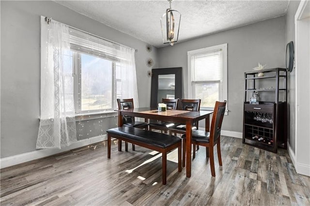 dining area with a textured ceiling, wood finished floors, and baseboards