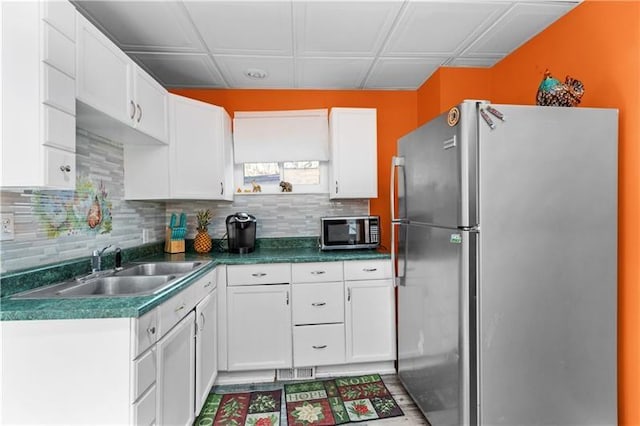 kitchen with a sink, white cabinetry, appliances with stainless steel finishes, backsplash, and dark countertops