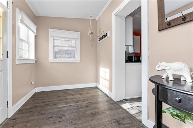 interior space with crown molding, baseboards, and wood finished floors