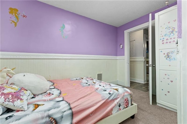 bedroom featuring a wainscoted wall, visible vents, and carpet flooring