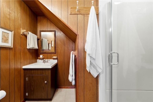 full bath featuring tile patterned floors, vanity, a shower with shower door, and wooden walls