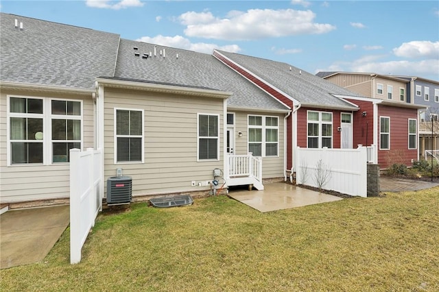 back of property featuring a patio, central AC unit, fence, a yard, and roof with shingles