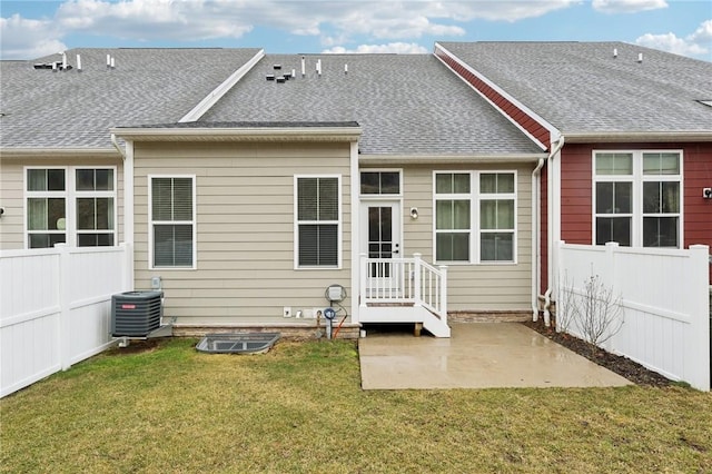 rear view of house featuring central AC unit, roof with shingles, fence, a yard, and a patio area