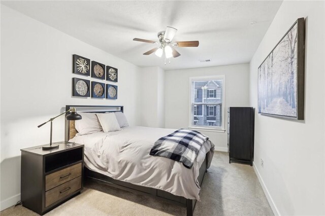 bedroom featuring light carpet, visible vents, baseboards, and a ceiling fan