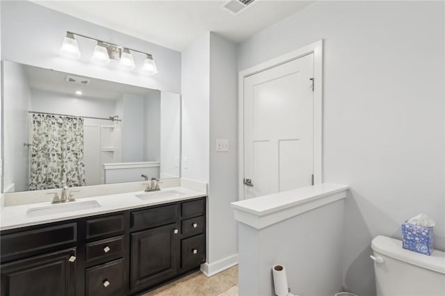 bathroom featuring visible vents, a sink, toilet, and double vanity