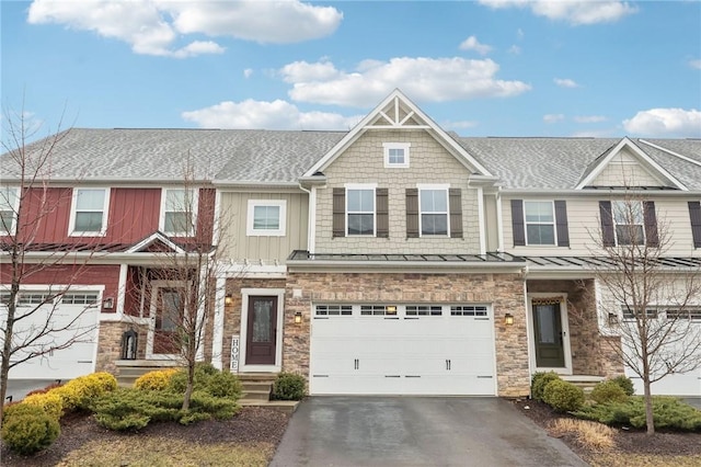 townhome / multi-family property featuring a garage, driveway, stone siding, roof with shingles, and board and batten siding