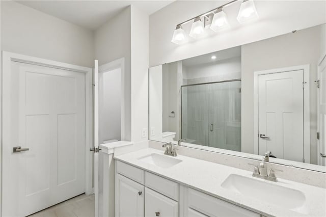 bathroom with double vanity, a stall shower, and a sink