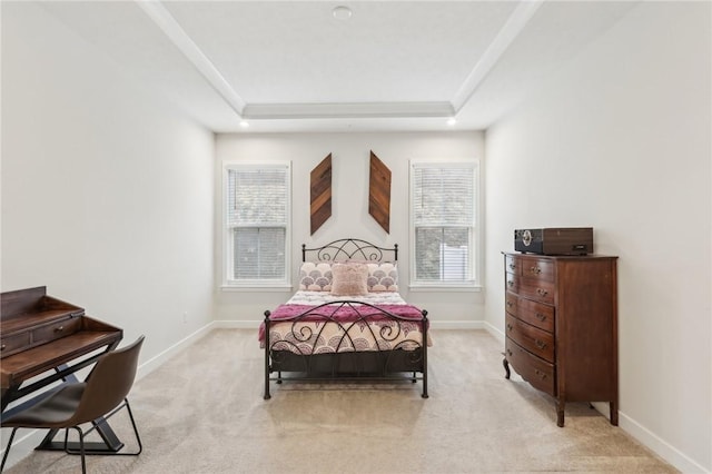 bedroom with a raised ceiling, light colored carpet, and baseboards