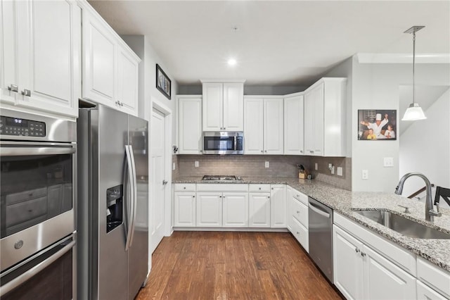 kitchen featuring appliances with stainless steel finishes, a sink, white cabinets, and decorative backsplash