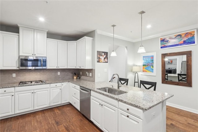 kitchen featuring stainless steel appliances, dark wood-type flooring, a peninsula, a sink, and tasteful backsplash