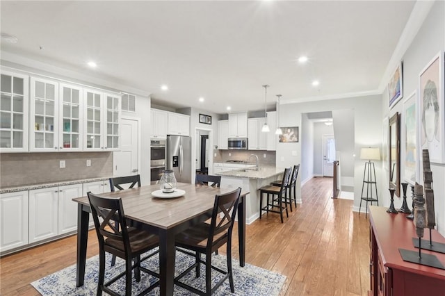 dining space featuring light wood-style floors, baseboards, crown molding, and recessed lighting