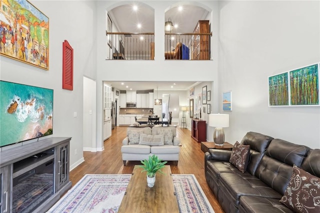 living area featuring light wood-style floors, a high ceiling, and baseboards