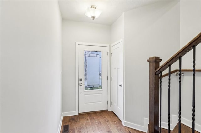 entryway with stairway, wood finished floors, visible vents, and baseboards