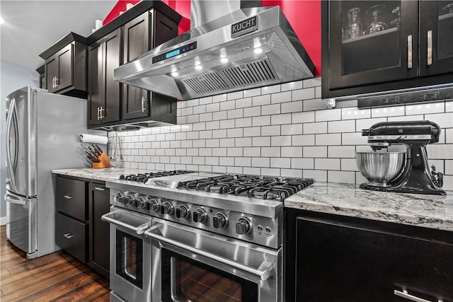 kitchen featuring appliances with stainless steel finishes, dark wood finished floors, wall chimney exhaust hood, and tasteful backsplash