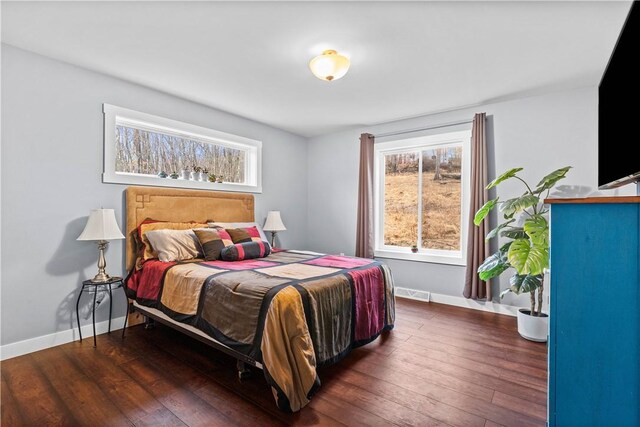 bedroom with hardwood / wood-style floors, visible vents, and baseboards