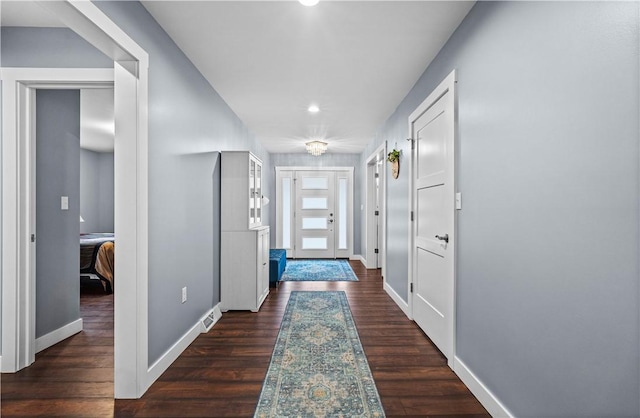 doorway featuring dark wood-style flooring and baseboards