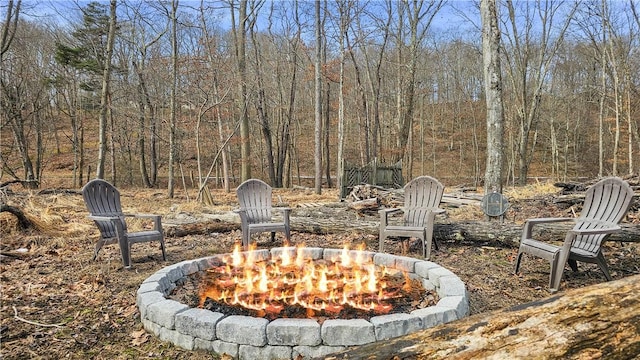 exterior space with a forest view and an outdoor fire pit