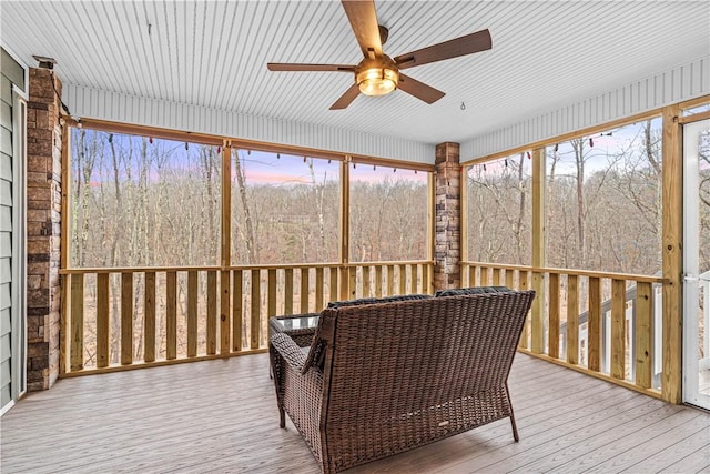 sunroom / solarium with a forest view and a ceiling fan