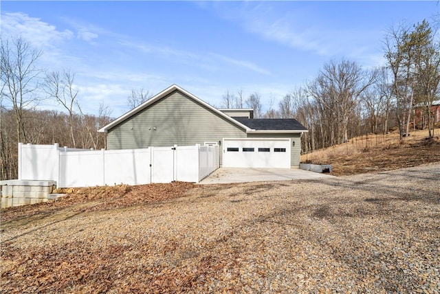 garage with gravel driveway and fence