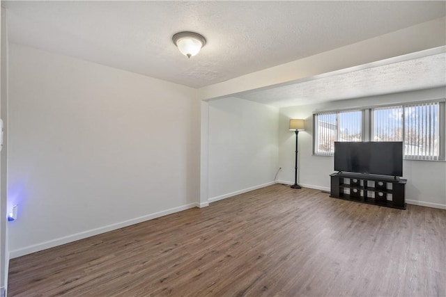 interior space with a textured ceiling, baseboards, and wood finished floors