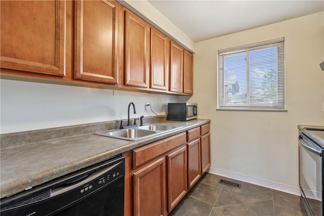 kitchen with dark tile patterned floors, black appliances, brown cabinetry, and a sink