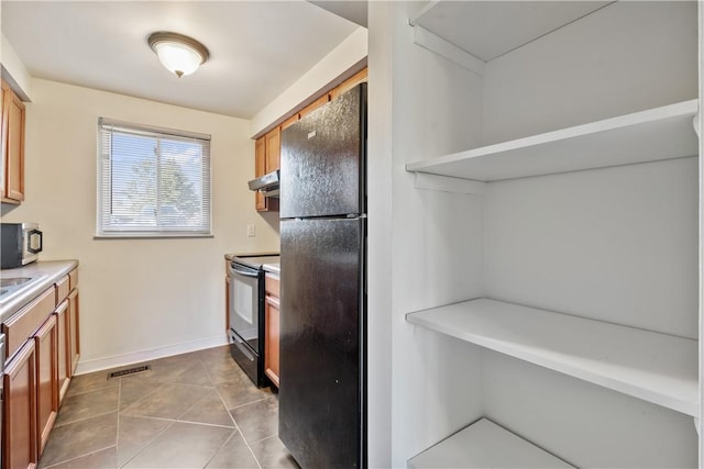 kitchen featuring baseboards, tile patterned flooring, under cabinet range hood, light countertops, and black appliances