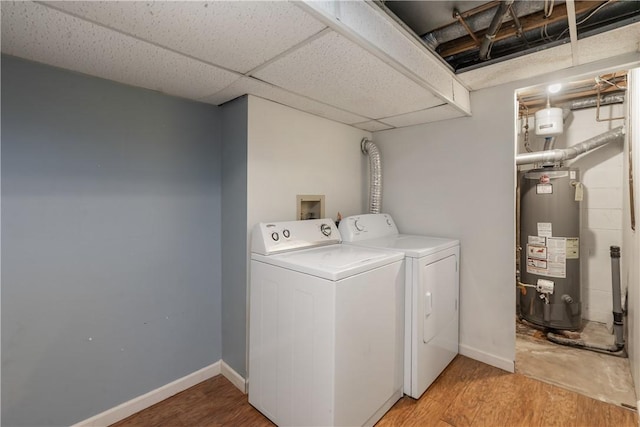 clothes washing area with light wood finished floors, water heater, baseboards, and independent washer and dryer