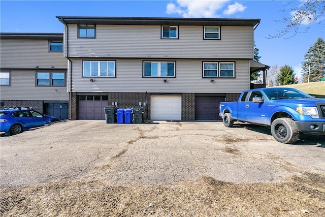 rear view of house with a garage, driveway, and brick siding