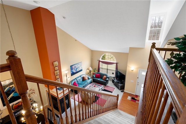 stairway featuring wood finished floors and high vaulted ceiling