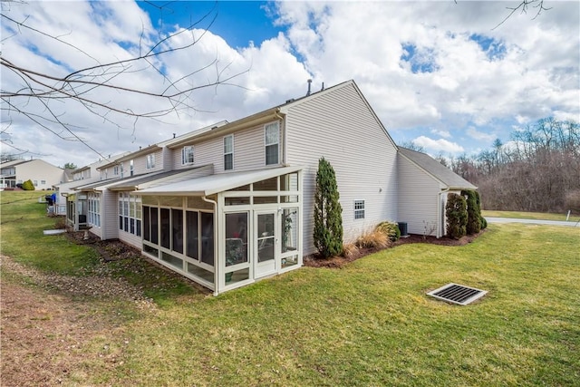 rear view of property featuring a sunroom, a yard, and central AC unit