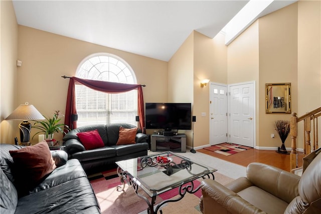 living room with high vaulted ceiling, stairway, a skylight, and baseboards