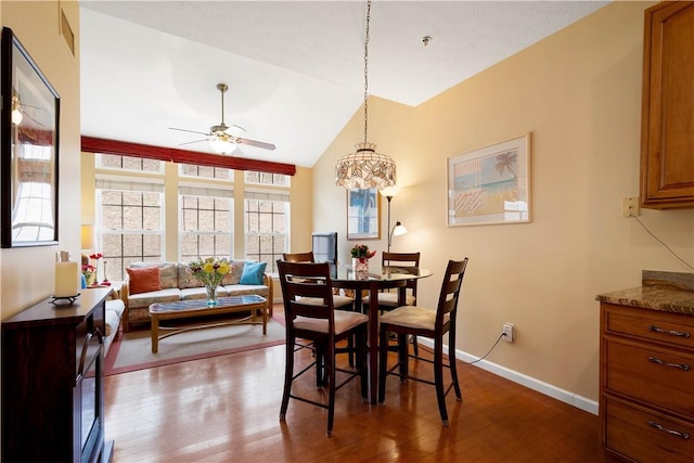dining space with vaulted ceiling, wood finished floors, visible vents, baseboards, and ceiling fan